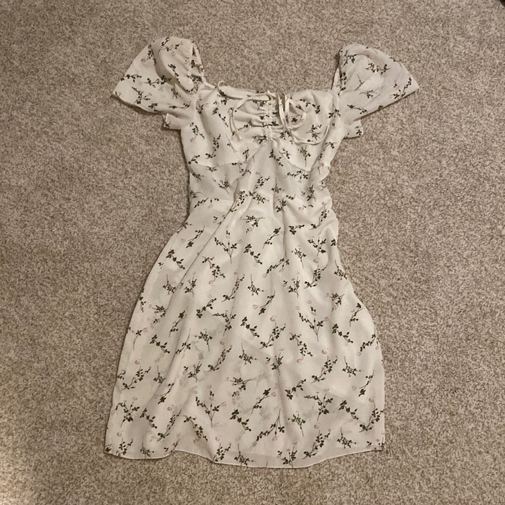 Medium, white dress with flower details, and soft, feminine sleeves.